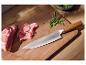 Couteau de chef avec manche en bois, jambon et roquette sur une planche à découper.