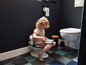 Une petite fille lit un livre sur un pot pour enfants dans une salle de bain.