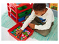 Un enfant joue avec des blocs LEGO colorés dans un bac rouge.