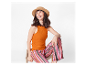 Femme en débardeur orange et pantalon rayé assise sur une chaise.