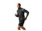 Homme souriant en gilet de course noir et manches longues grises, courant.