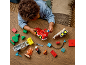 Un tout-petit joue avec un camion de pompiers rouge et des blocs de construction sur une table en bois.