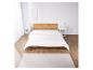 Une couette blanche sur un cadre de lit en bois dans une chambre à coucher avec un tapis.