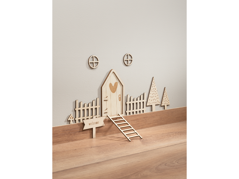 Décorations murales en bois, incluant une maison de fées, des clôtures et des arbres.