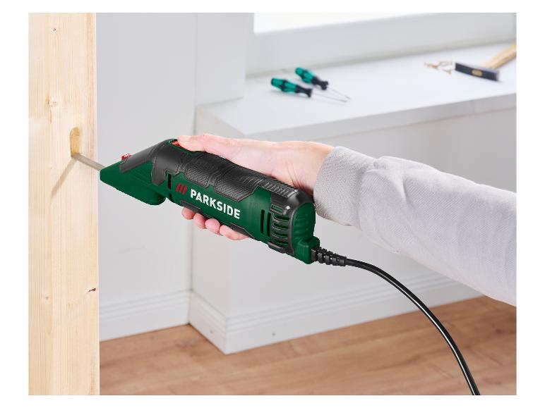 Une main tient un ciseau électrique qui sculpte un trou dans une poutre en bois.