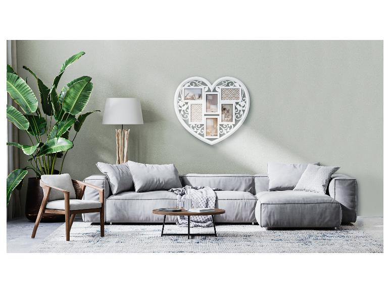 Un canapé gris avec des coussins et une table basse dans un salon avec un cadre photo en forme de cœur.