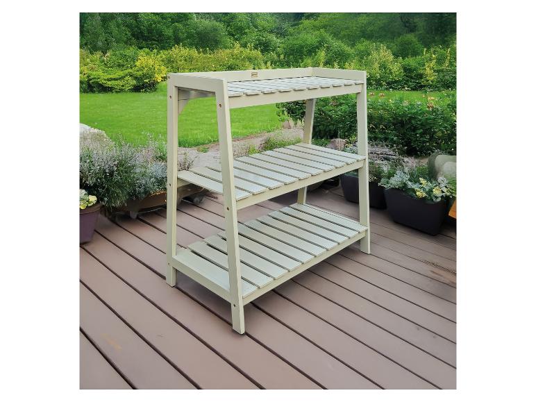 Banc à plantes vert à trois étagères sur une terrasse en bois entourée de verdure.