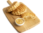 Chaussons aux pommes dorés et un bol de compote de pommes sur une planche en bois.