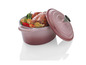 Une cocotte en fonte rose avec un poulet rôti et des légumes.