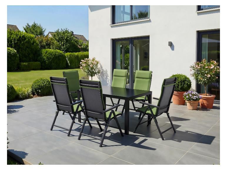 Ensemble de salle à manger d'extérieur avec table noire et chaises vertes sur une terrasse près d'une maison moderne.