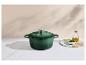 Cocotte en fonte verte avec couvercle, huile d'olive et ciboulette hachée sur une planche.
