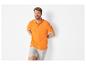 Homme souriant portant un polo orange et un short gris.