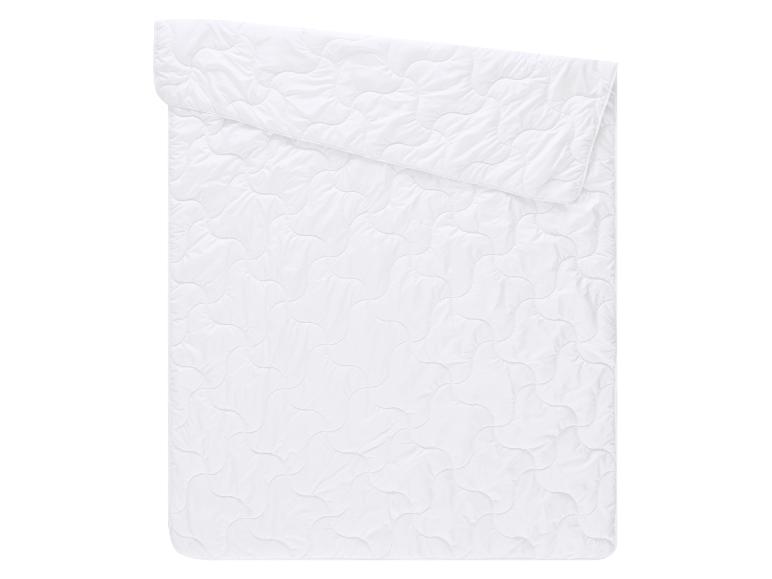 Couette blanche matelassée avec un motif ondulé, pliée sur le dessus.