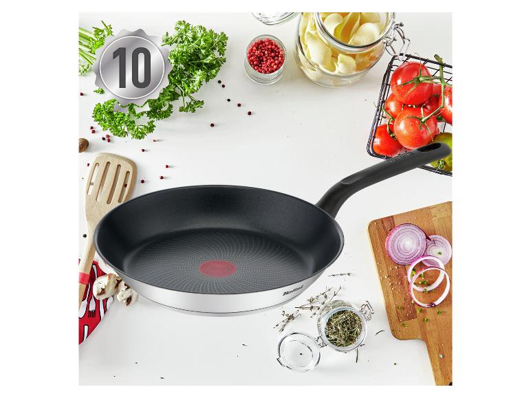 Poêle à frire avec des ingrédients de cuisine comme des herbes, des tomates et des pâtes, avec un badge '10'.