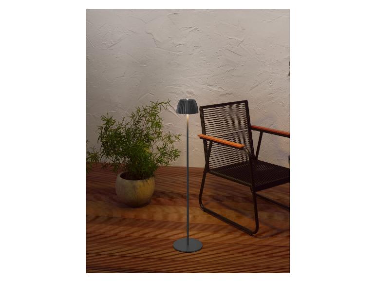 Lampadaire moderne et plante en pot sur une terrasse en bois avec une chaise.