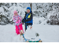 Deux enfants en vêtements d'hiver avec une luge et un petit bonhomme de neige dans un paysage enneigé.