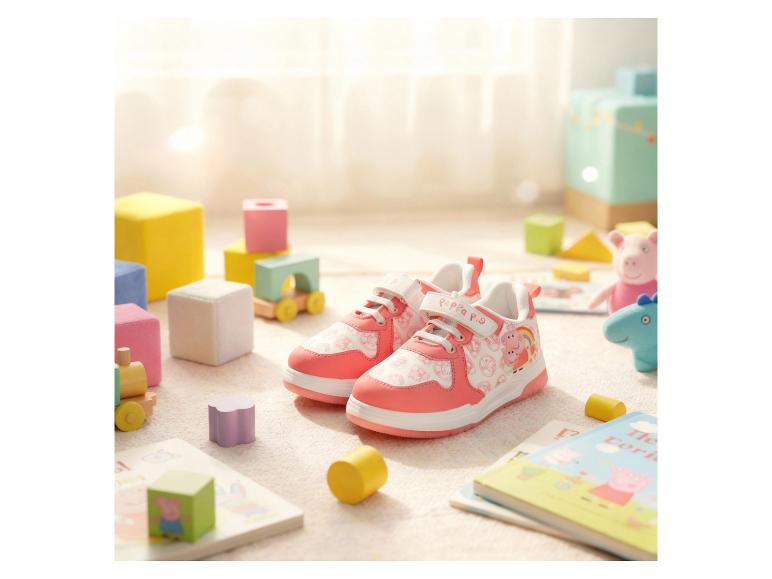 Chaussures roses pour enfants avec personnages de dessins animés, entourées de jouets et de livres.