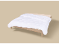 Couette blanche sur un cadre de lit en bois avec un matelas beige clair.