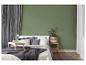 Chambre à coucher avec lit, table de chevet, plantes et murs verts.