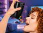 Une femme mange des en-cas d'un distributeur de snacks Gourmetmaxx noir.