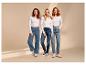 Trois femmes portent des t-shirts blancs à manches longues et des jeans, posant sur un fond beige.