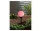 Lampadaire d'extérieur sphérique rose et plantes vertes.