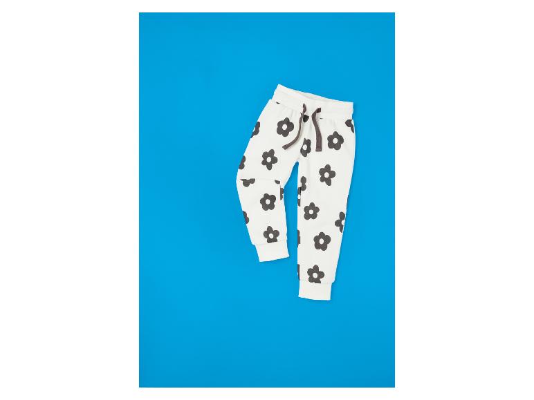Pantalon blanc à fleurs noires sur fond bleu.