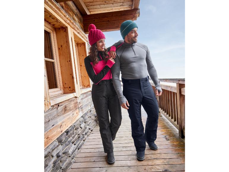 Couple en pantalons et sweat-shirts d'hiver sur une terrasse en bois.