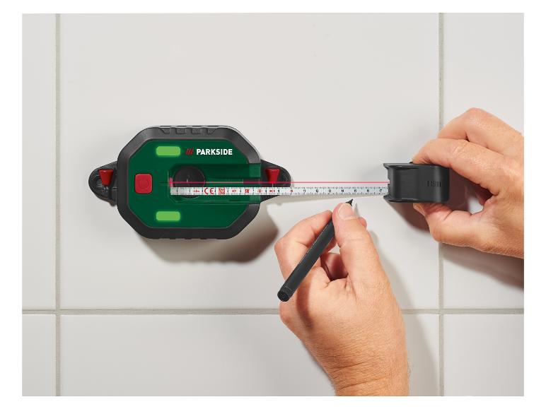 Un niveau laser Parkside avec un ruban à mesurer et un stylo pour marquer une ligne sur un mur carrelé.