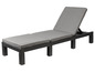 Un chaise longue en osier noir avec des coussins gris.