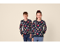 Un garçon et une fille sourient en portant des pulls de Noël bleu marine assortis.