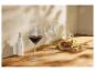 Verres de vin rouge et vides, avec des raisins, du fromage et de l'huile d'olive sur une table en bois.