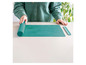 Un tapis de cuisson en silicone vert Coox, roulé et prêt à l'emploi.