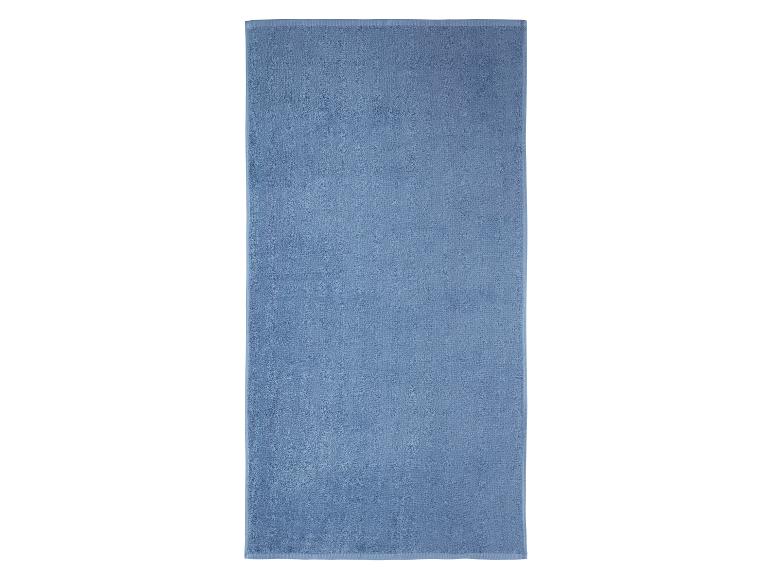 Serviette de bain bleu clair, pliée, sur fond blanc.