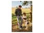 Homme en veste verte et pantalon cargo avec un chien dans un cadre rural.