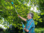 Un homme utilise un sécateur Gardena pour tailler des branches dans le jardin.