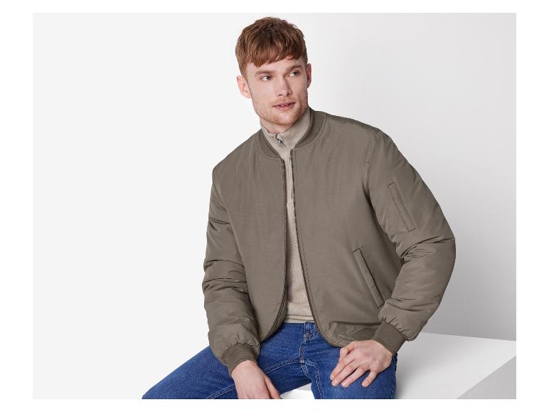 Un jeune homme portant une veste bomber olive.