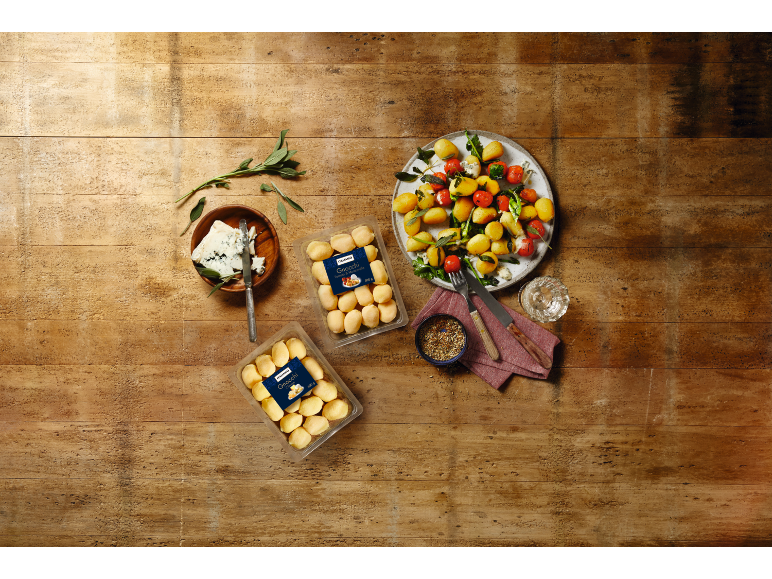 Gnocchis emballés et cuits avec tomates cerises, pommes de terre et fromage bleu sur bois.