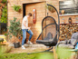 Un homme marche vers un fauteuil suspendu dans un jardin.