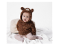 Bébé adorable dans une combinaison en peluche marron ours.