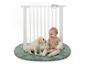 Bébé et chiot jouant sur un tapis rond vert avec une barrière de sécurité blanche.