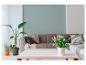 Salon avec un canapé gris, des coussins, des plantes et une table basse blanche.