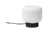 Lampe de table blanche avec abat-jour nervuré et base noire, avec câble d'alimentation visible.