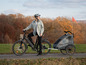 Une femme fait du vélo électrique avec une remorque à vélo Qeridoo pour enfant.