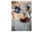 Couple souriant allongé dans un lit avec des draps fleuris et des pyjamas.