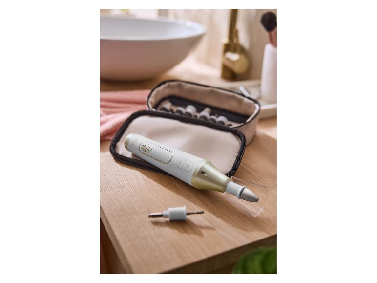 Kit manucure et pédicure avec lime électrique sur un comptoir de salle de bain en bois.