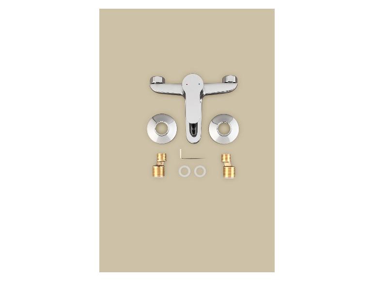 Robinet chromé avec pièces d'installation sur fond beige.