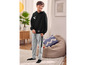Un garçon porte un sweat à capuche noir avec un imprimé skateboard et un pantalon de survêtement gris.
