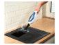Nettoyage d'une plaque de cuisson noire avec un nettoyeur vapeur à main.