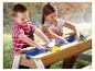 Deux enfants jouent avec une table à eau en bois avec des bateaux jouets.